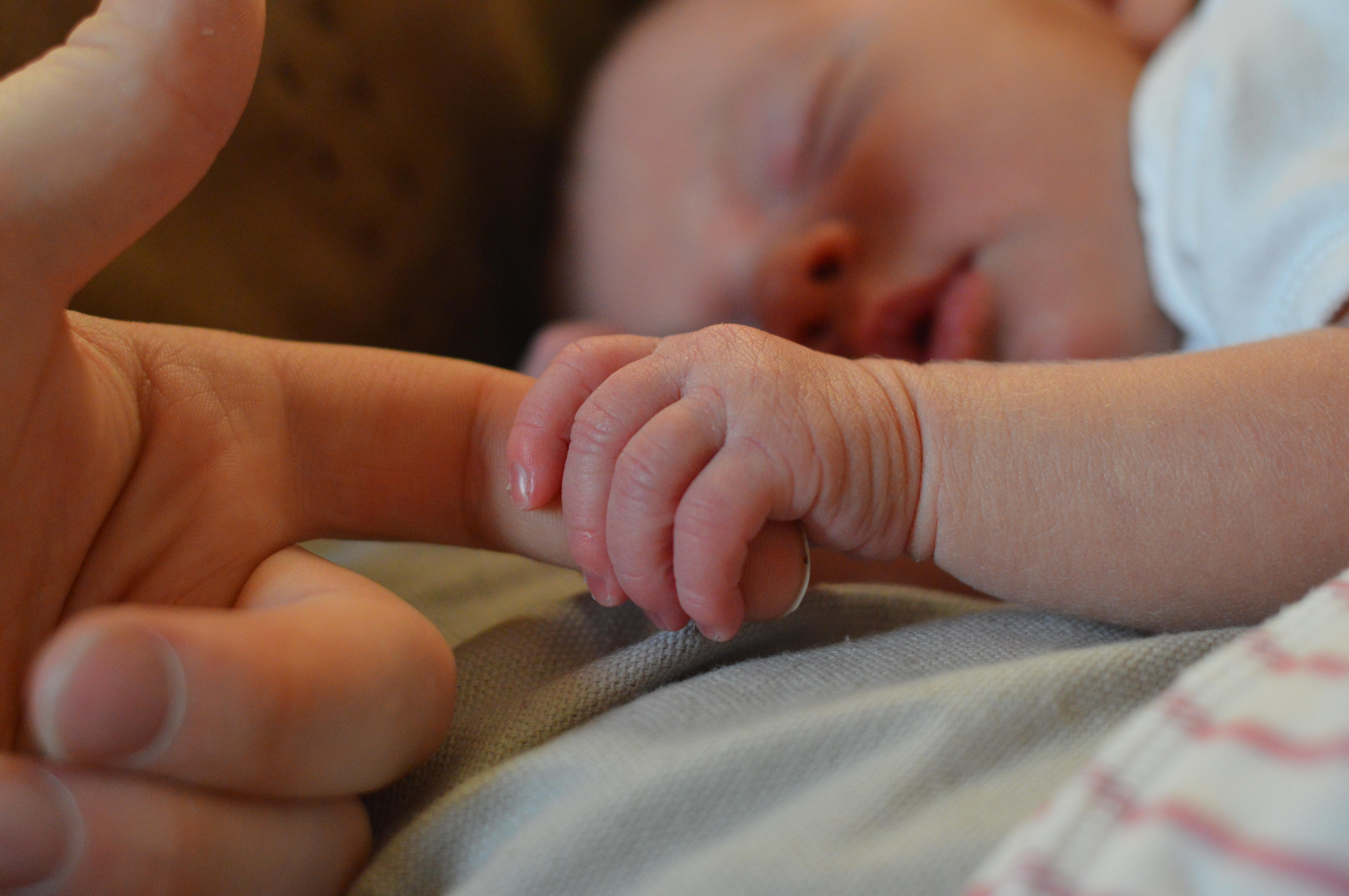 Bambino che afferra il dito di mamma