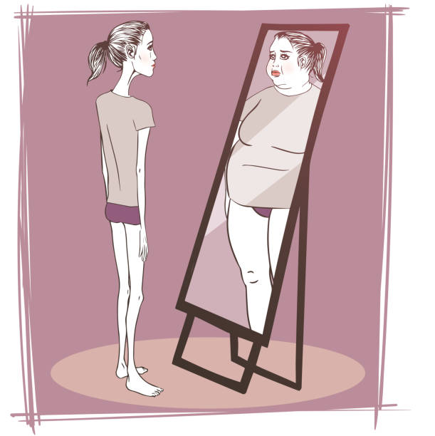 Young woman suffering from anorexia looking in the mirror